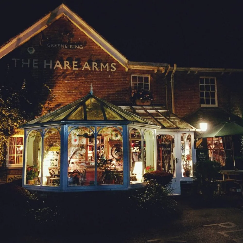 The Hare Arms illuminated at night with its conservatory and traditional brick exterior